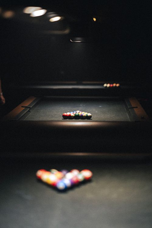 Vista de una mesa de billar con bolas alineadas en forma de corazón bajo iluminación suave.